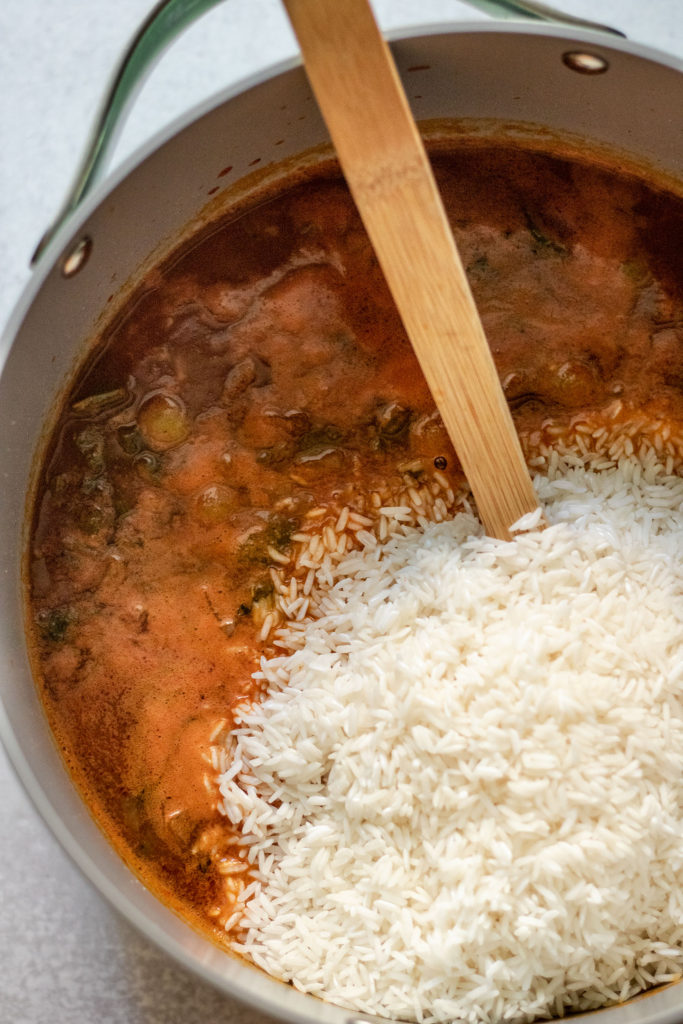 Mixing white rice into the tomato mix and pigeon peas.