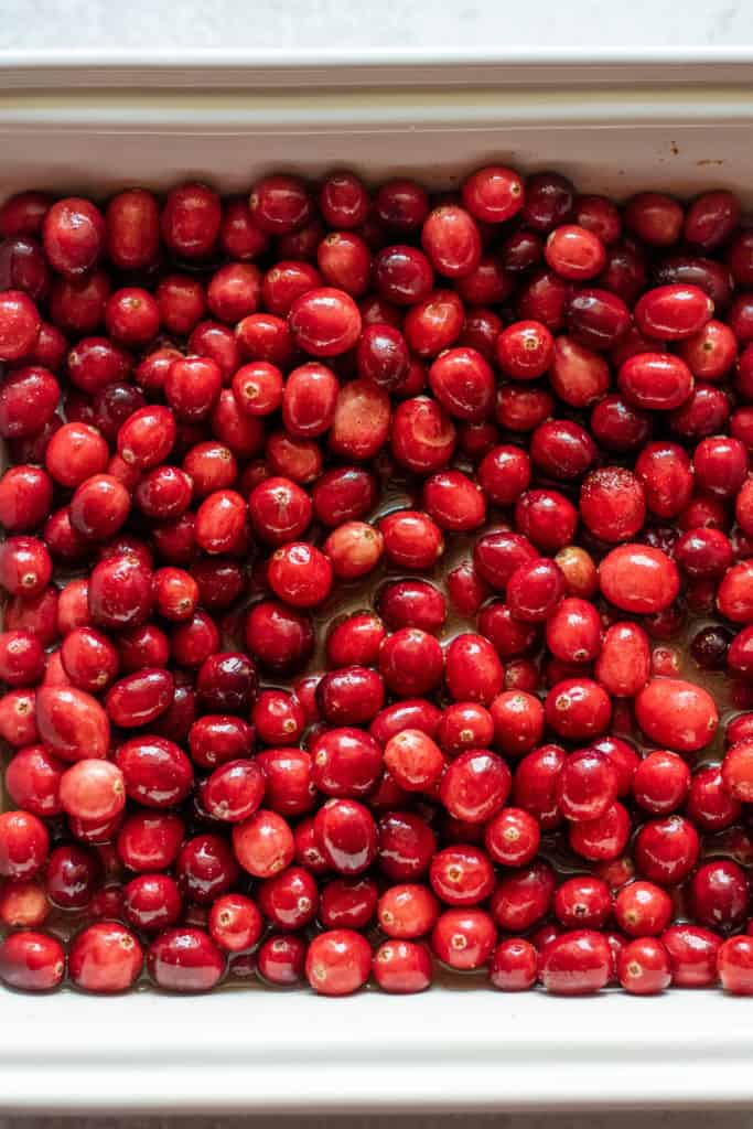 Cranberries placed in a baking dish with maple syrup and water.