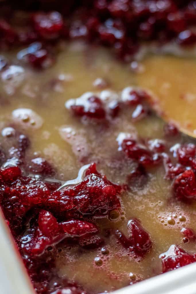 Stirring the cooked and mashed cranberries with orange juice and salt.