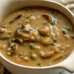 Mushroom gravy topped with fresh thyme and served in a gravy boat.