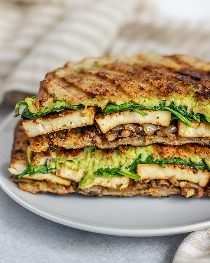 Close up of the inside of a vegan panini sandwich filled with tofu, avocado and avocado.
