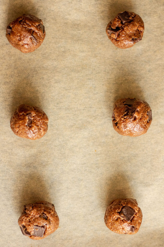 Cookie dough balls rolled smooth and placed on a baking tray.