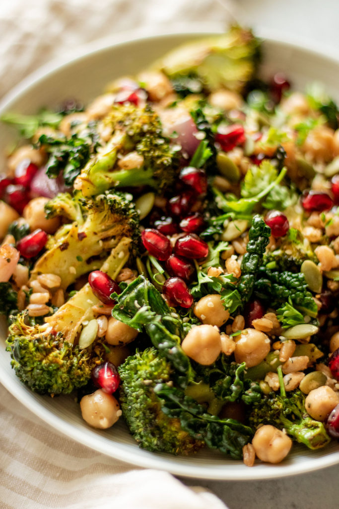 Side view of a plate of farro salad topped with pomegranate and parsley.