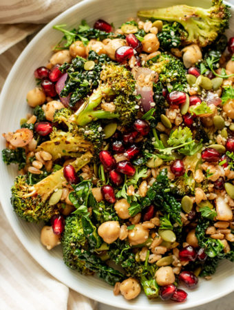 Close up view of a bowl of farro and kale salad topped with pomegranate.