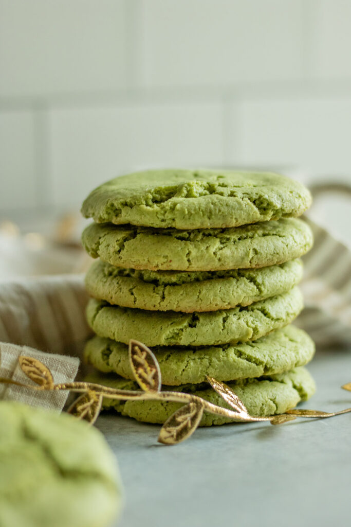 Stack of matcha cookies with a kitchen napkin in behind the stack.