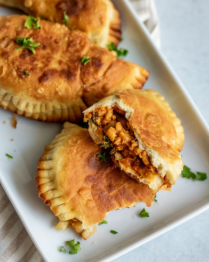 Close up of an open pastelito showing the filling on a plate.