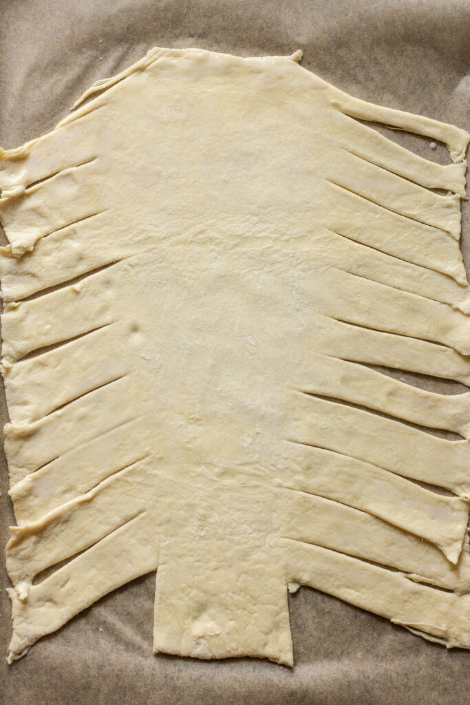 Puff pastry with strips cut into either side of the pastry.