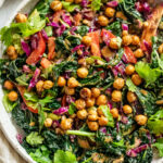 Large close up view of a bowl of kale crunch salad topped with roasted chickpeas.