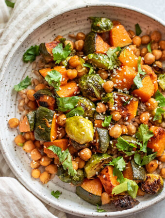 Close up view of a bowl of farro topped with roasted squash, brussel sprouts coated in a sweet miso sauce.