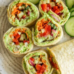 Bite sized veggie pinwheels presented on a platter with cucumber slices.