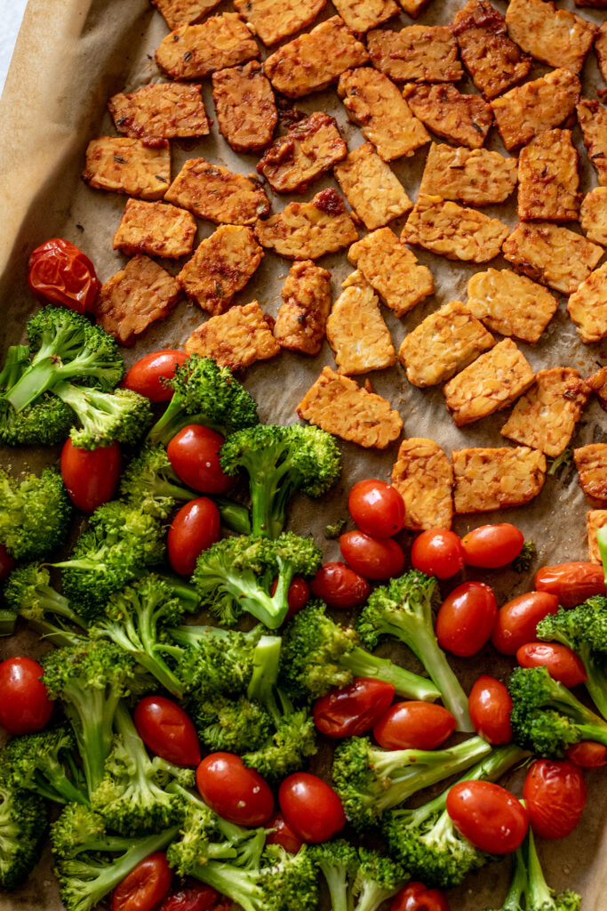 Baking tray with marinated tempeh, broccoli and cherry tomatoes.