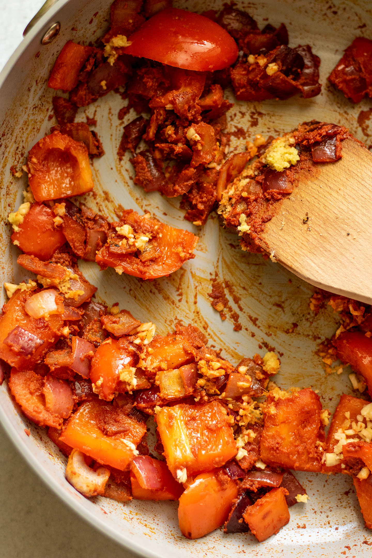 Sautéing the red curry paste into the vegetables in a pan.