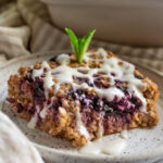 Big slice of lemon blueberry oatmeal topped with lemon yogurt and a fresf piece of mint on top.