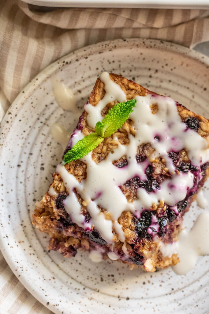 Top down view of a square piece of baked oatmeal topped with vegan yogurt and fresh mint.