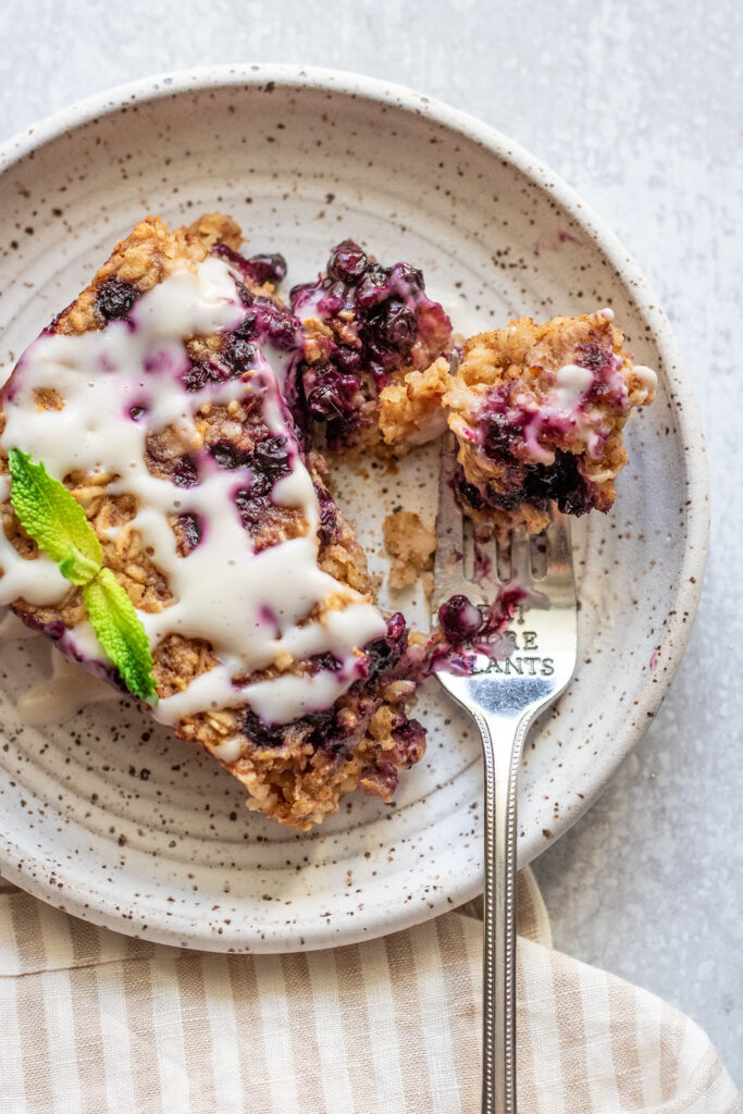 Taking a forkful of baked oats showing the gooey blueberry center.