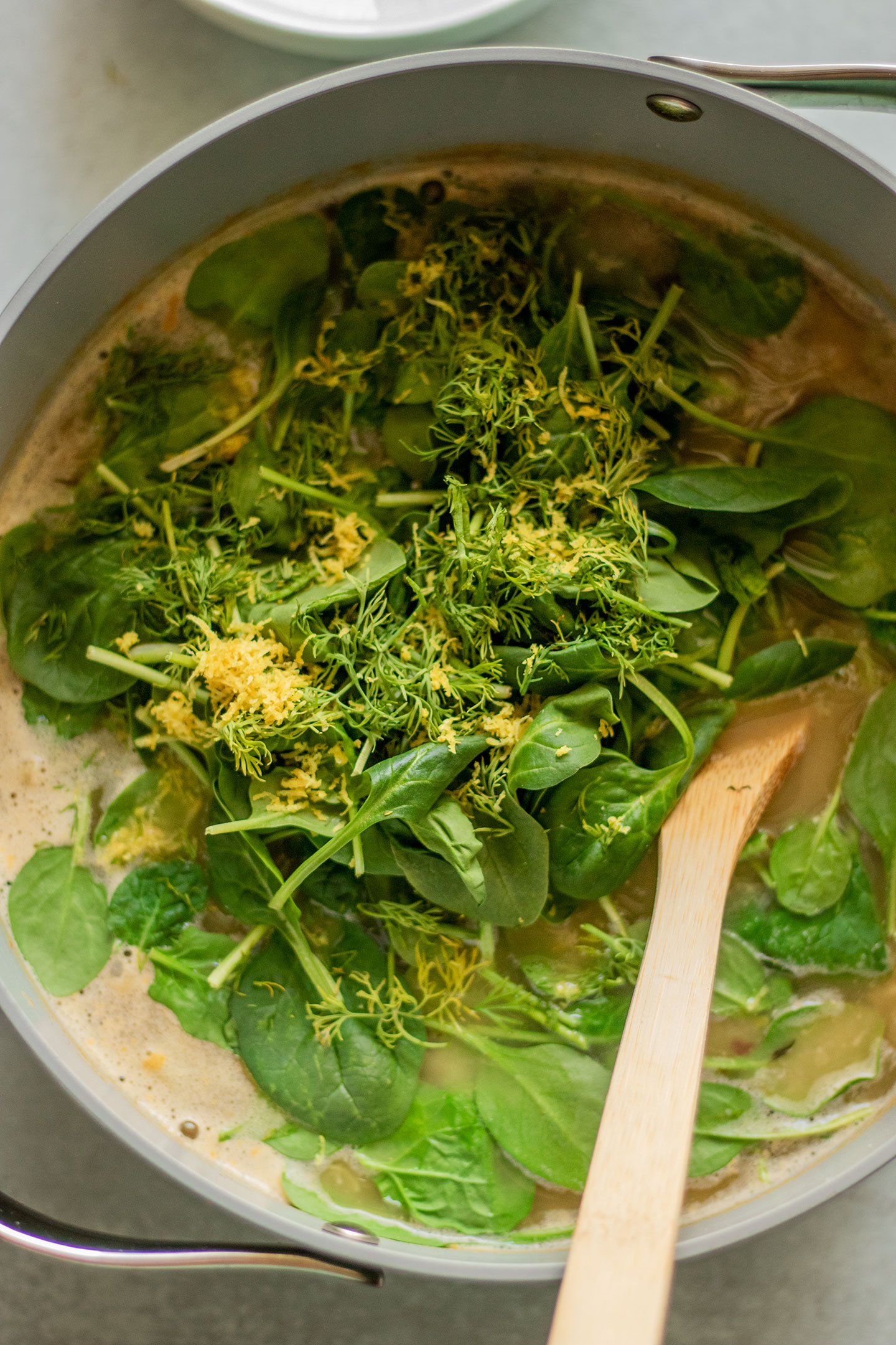 Adding spinach, lemon zest and dill to the soup pot after the potatoes cooked through.