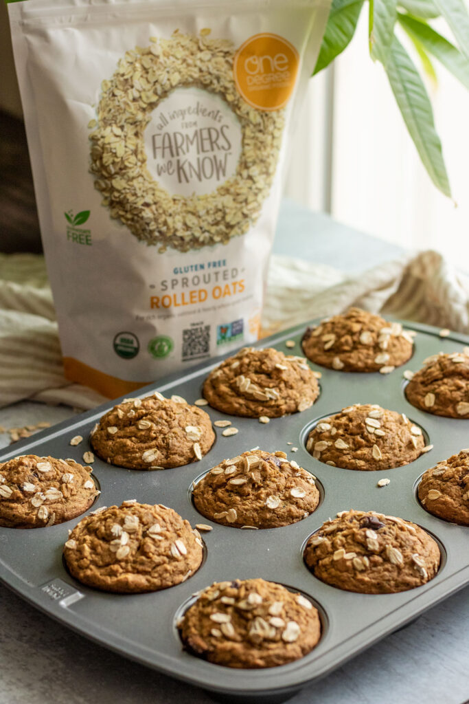 A bag of high soluble fiber containing oats placed next to a tray of baked zucchini muffins.