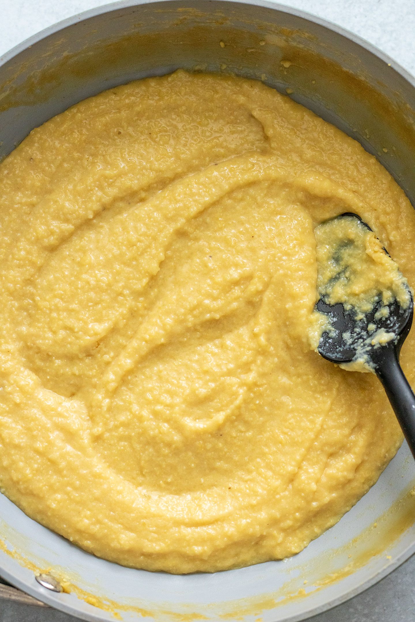 Stirring polenta in a sauce pan as it thickens.