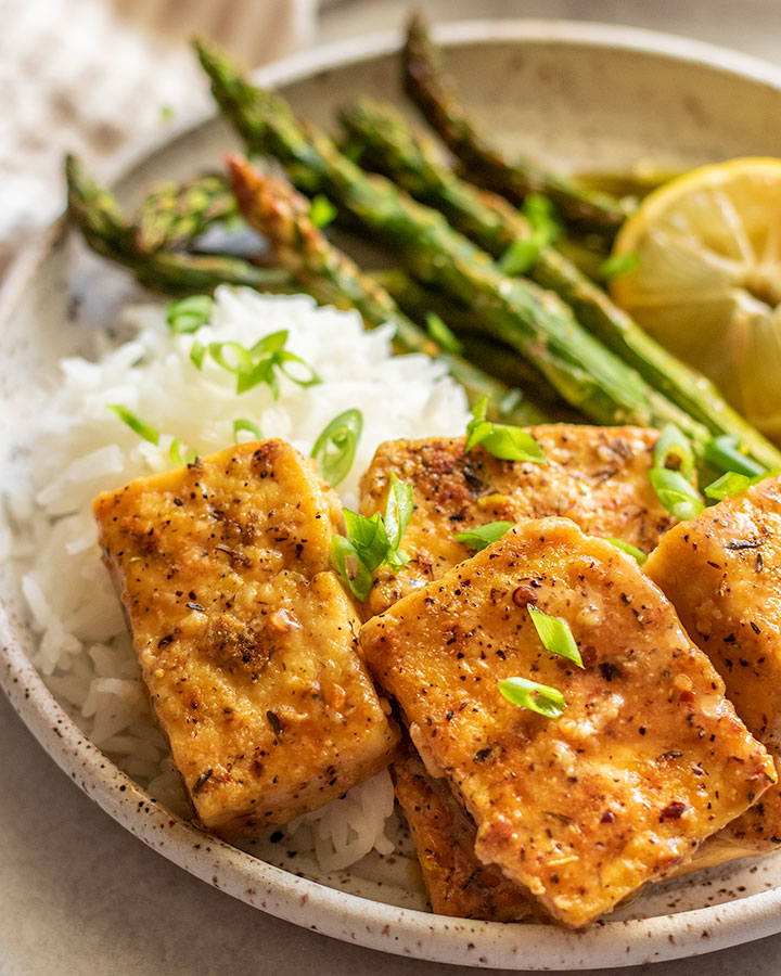 Seasoned tofu with lemon served with rice and asparagus.