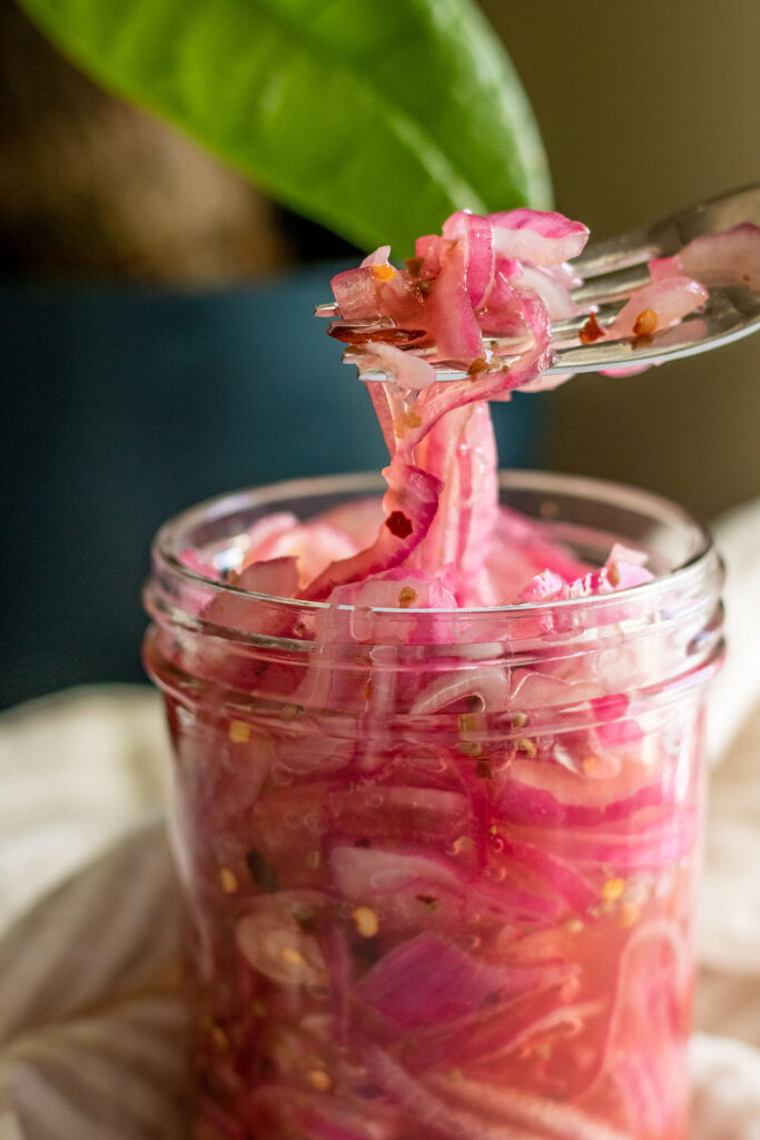 Pulling some fully cured pickled onions straight from the jar with a fork.