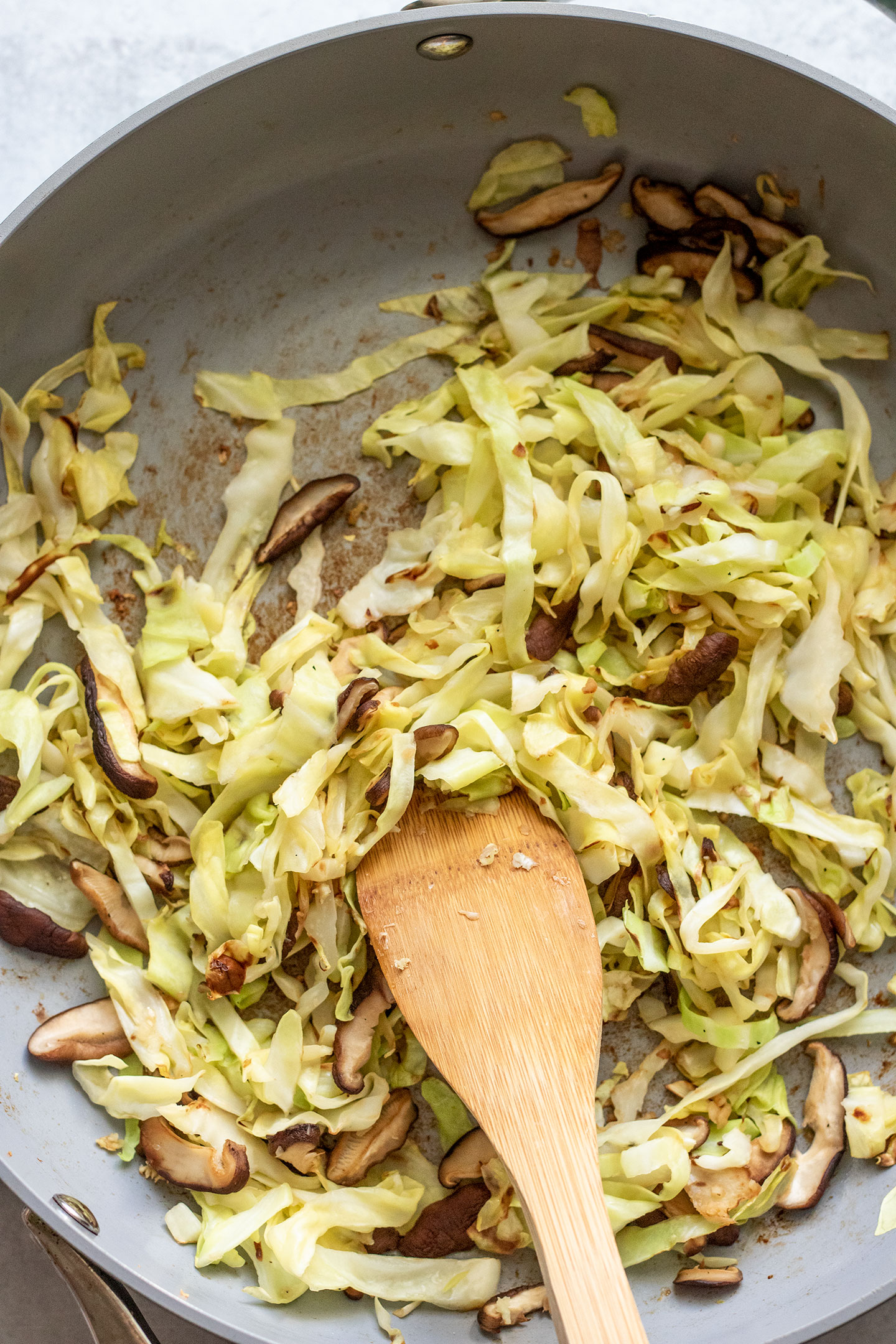 Sauteing the cabbage and mushrooms together in a pan with minced garlic.