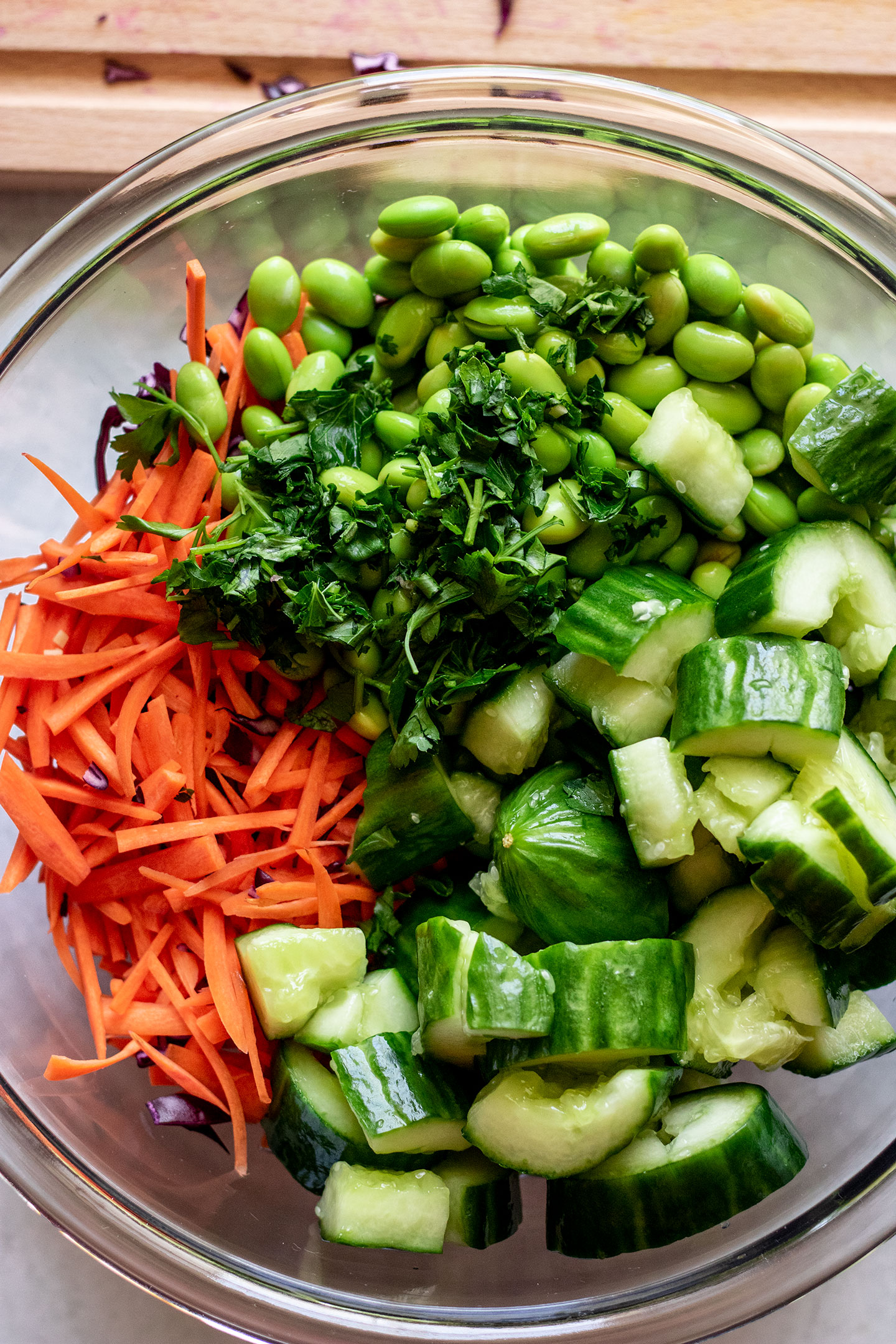 Bowl of edamame, smashed cucumber, cabbage, carrots and herbs.