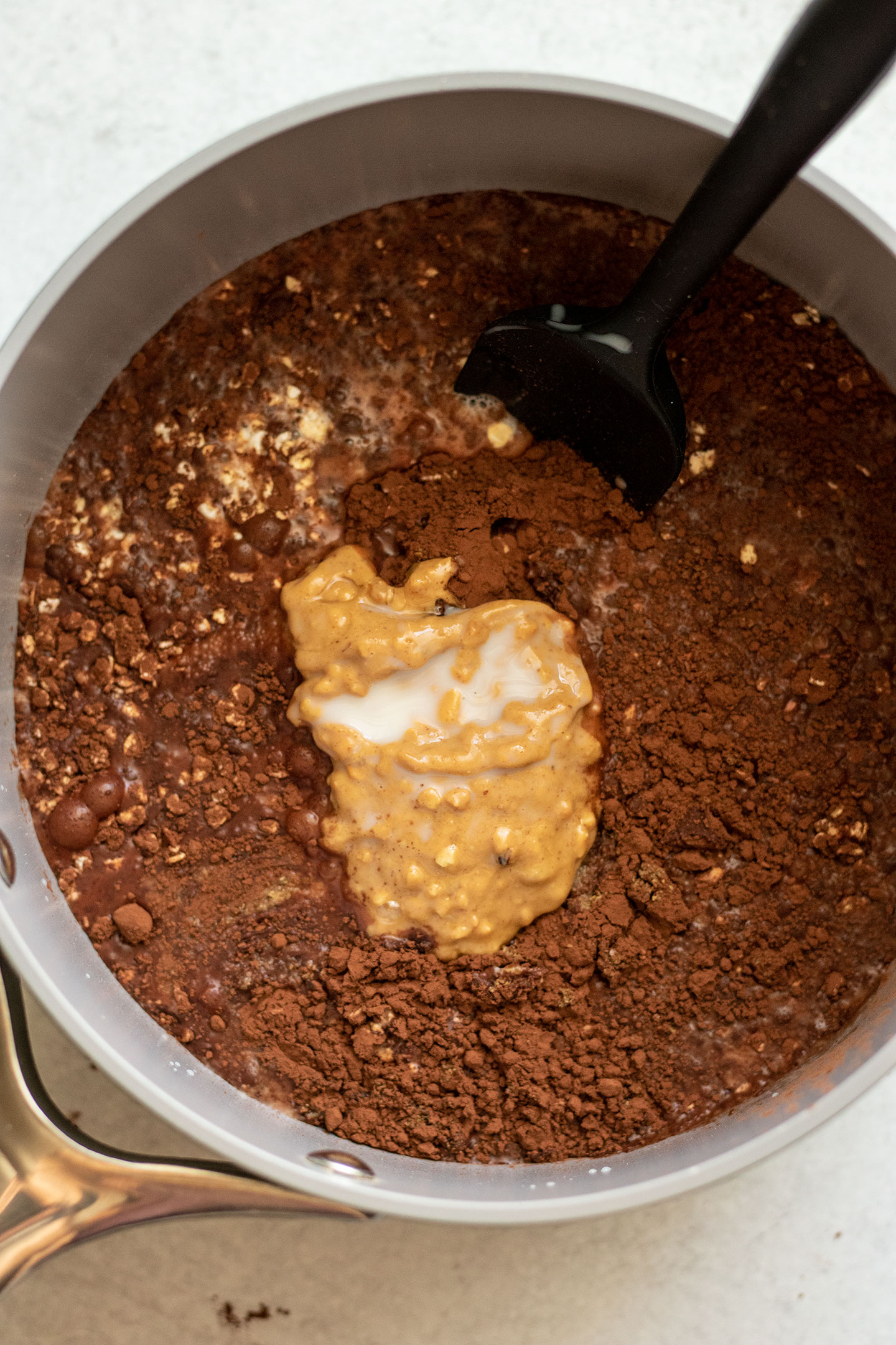 Mixing all the dry and wet oatmeal ingredients together in a sauce pan with a spatula.