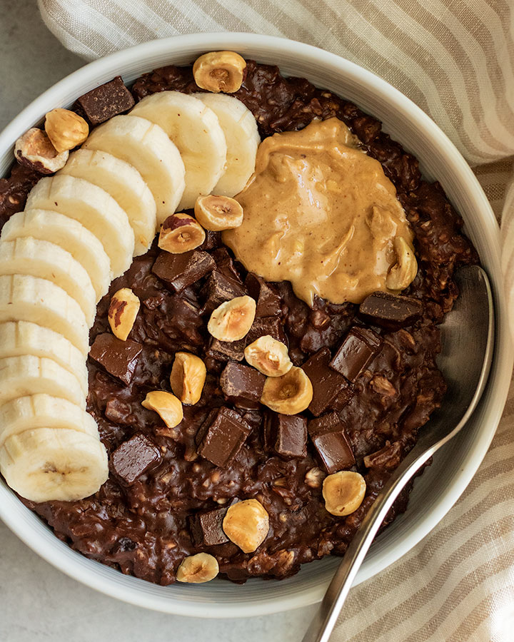 Fudgy creamy oatmeal topped with banana slices, roasted hazelnuts and chocolate chips.