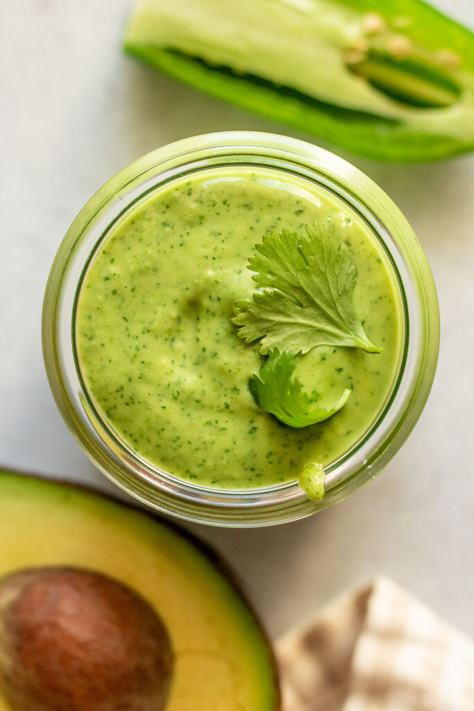 Top down view of the dressing placed in a jar with a cilantro leaf on top.