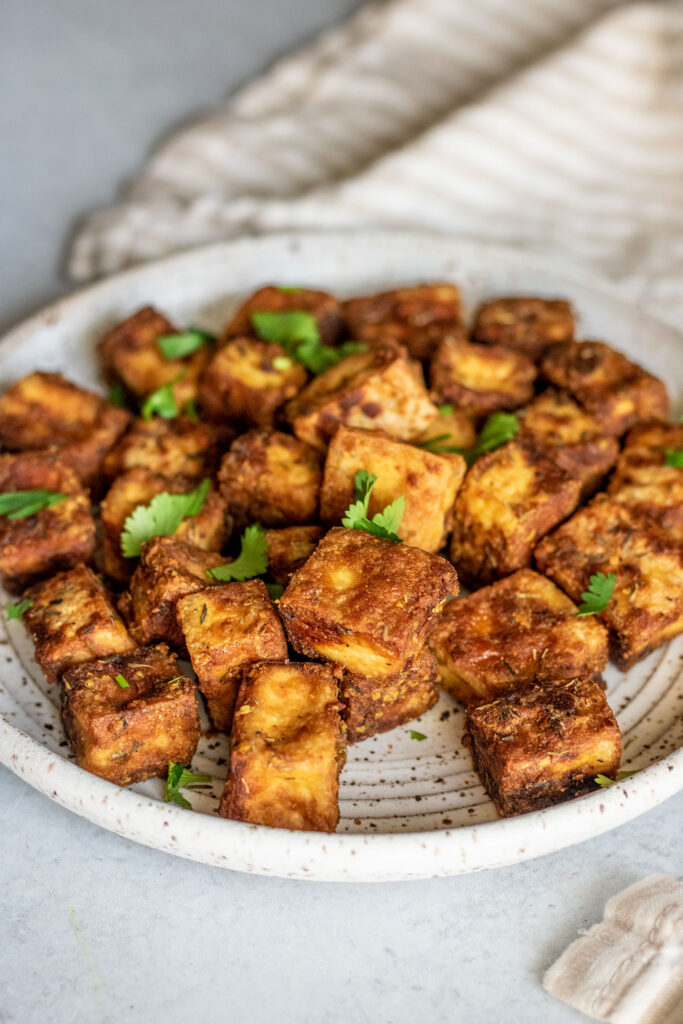 Side view of a plate of baked tofu topped with cilantro.