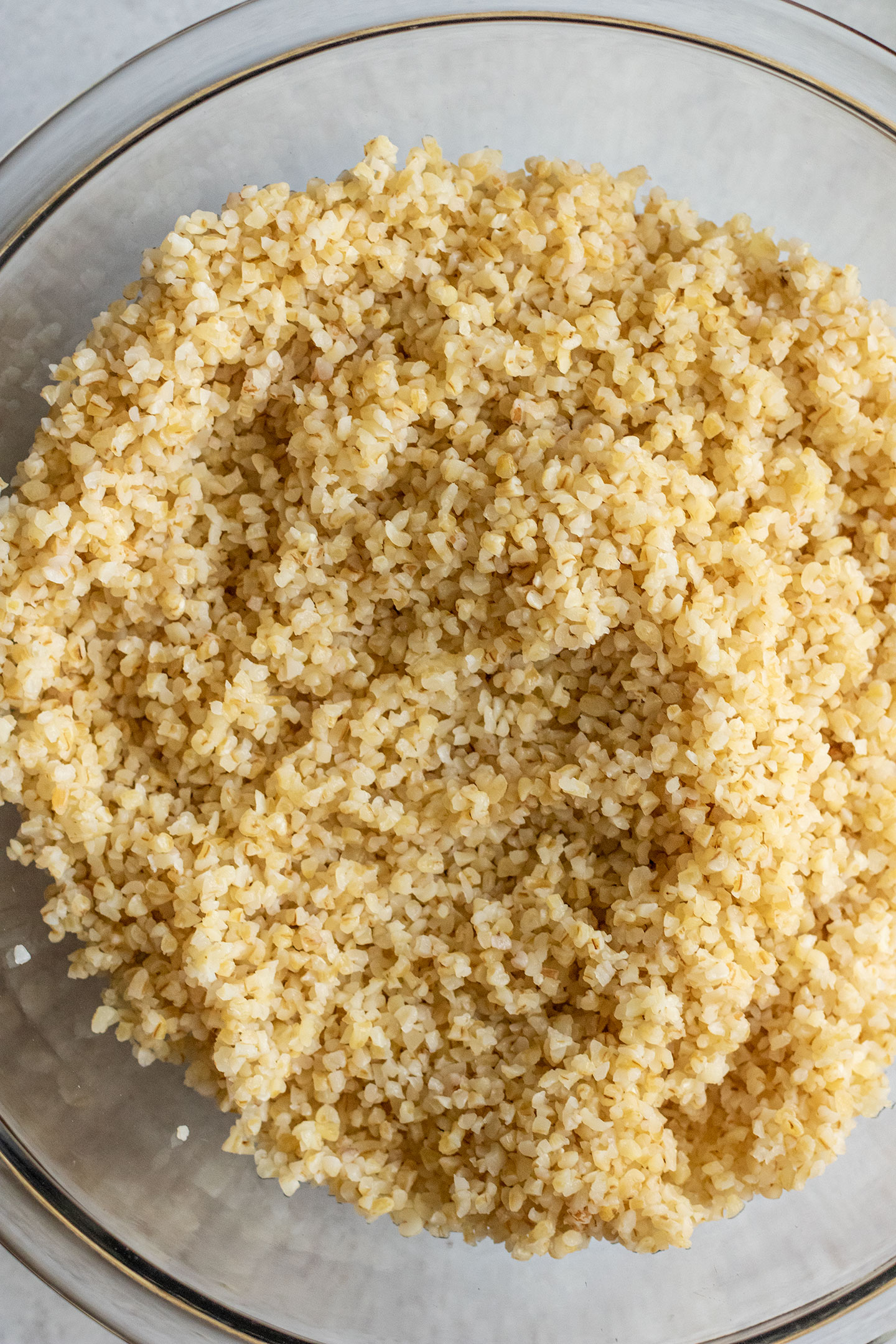 Soaked bulgur after being drained and placed in a glass bowl.