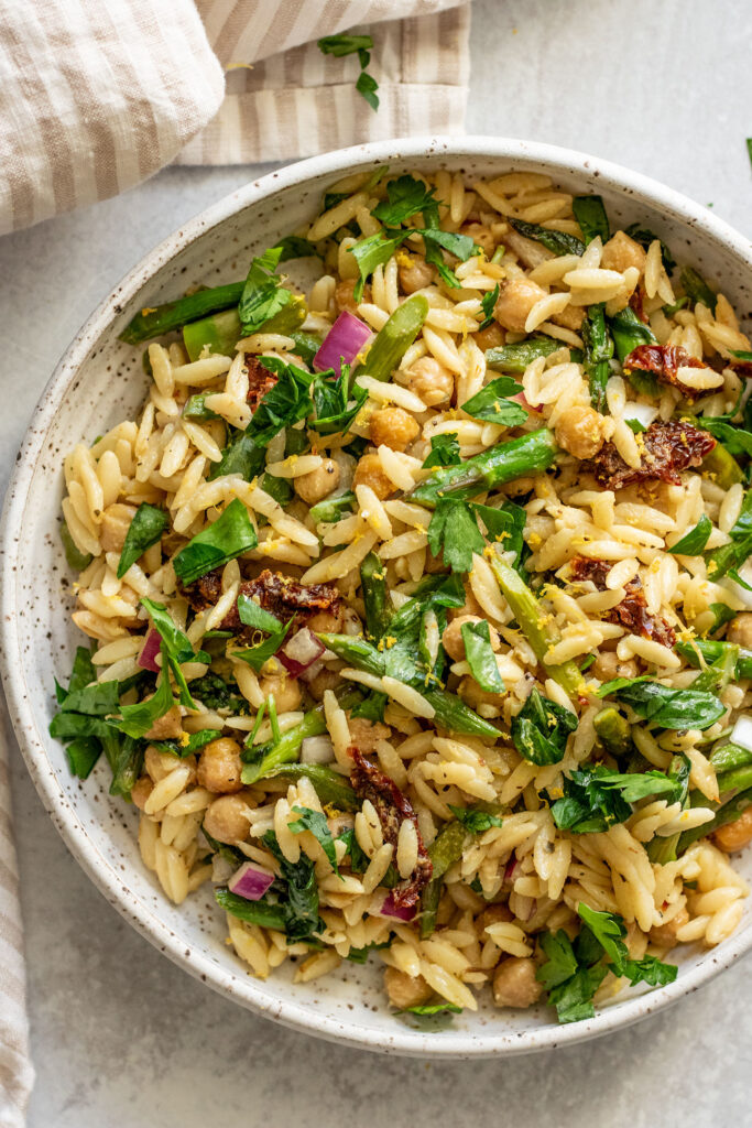 Close up of a bowl of lemon orzo pasta mixed with asparagus.