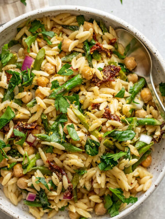 Close up of the orzo salad mixed with asparagus, chickpeas, sun-dried tomatoes and fresh basil.