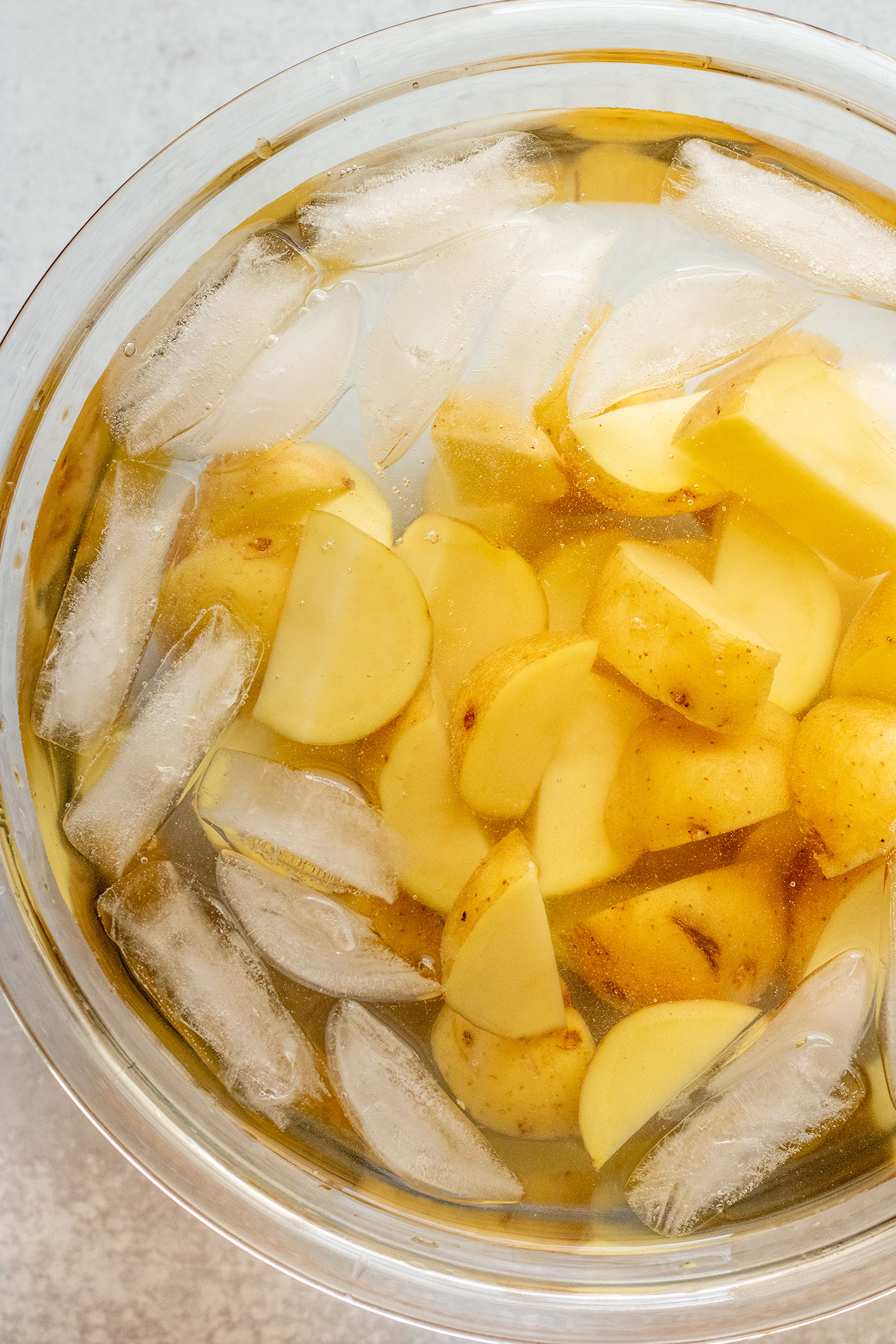 Chopped potatoes being soaked in ice cold water.
