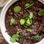 Creamy refried black beans topped with jalapeno slices and cilantro.