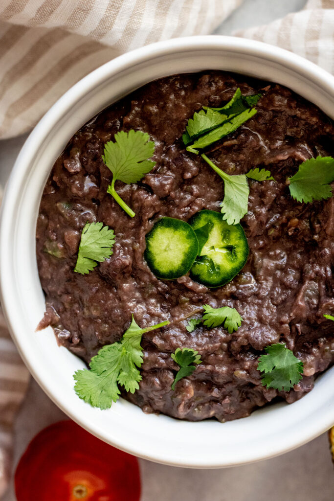 Creamy refried black beans topped with jalapeno slices and cilantro.