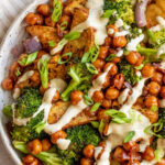 Close up shot of tahini sauce covered bbq chickpeas, broccoli and seasoned potatoes.