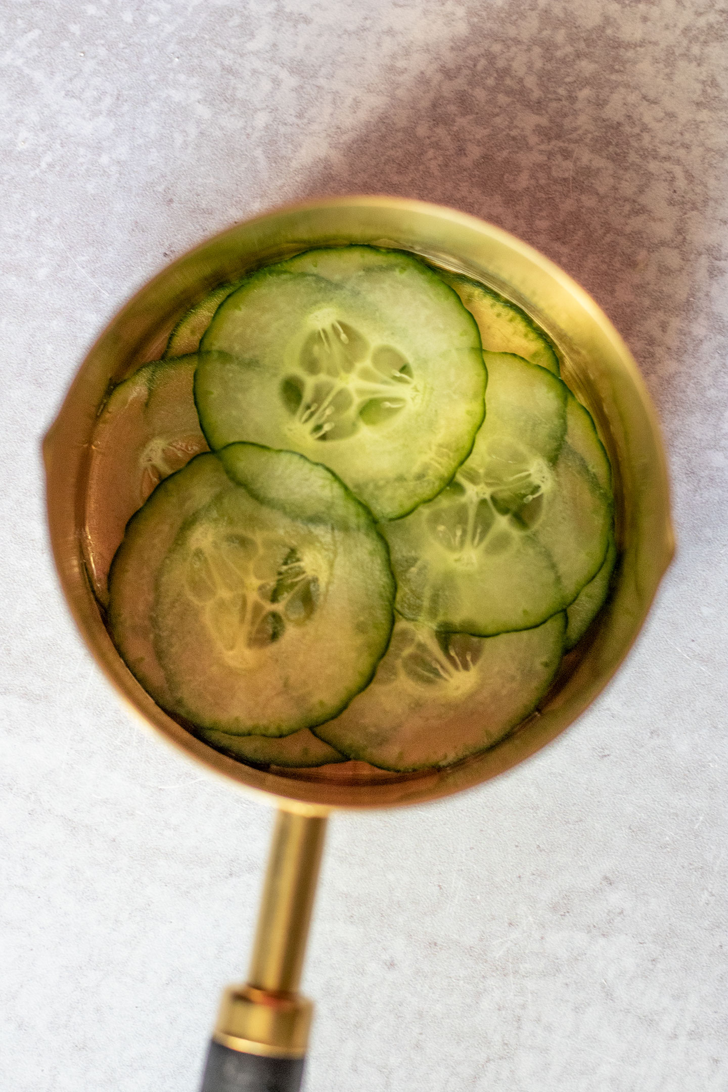 Cucumbers layered at the bottom of a large flat measuring cup.