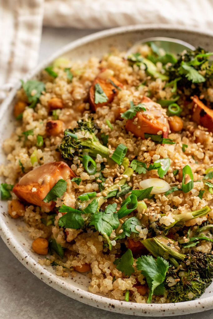 Side view of quinoa salad, sweet potato and roasted broccoli on a plate.