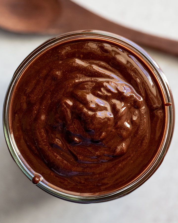 Top down view of a full jar of creamy chocolate hazelnut spread.