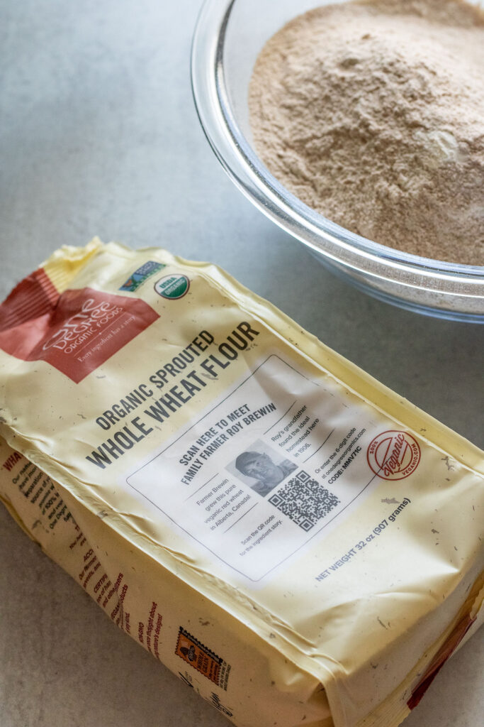 Measuring out whole wheat flour from One Degree Organics into a glass bowl.