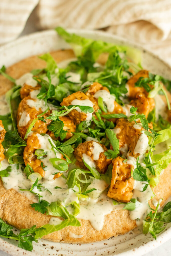 Side view of a buffalo tofu wrap topped with extra ranch dressing and scallions.