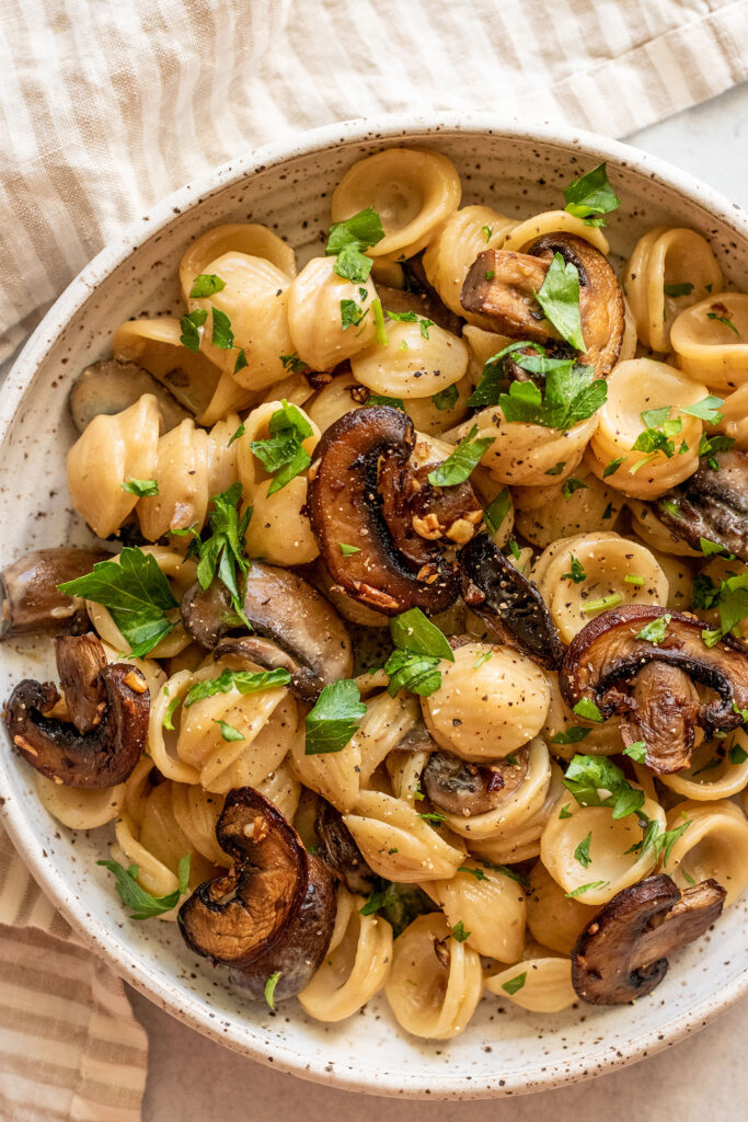 Bowl of spicy miso pasta topped with extra pan-fried mushrooms and parsley.