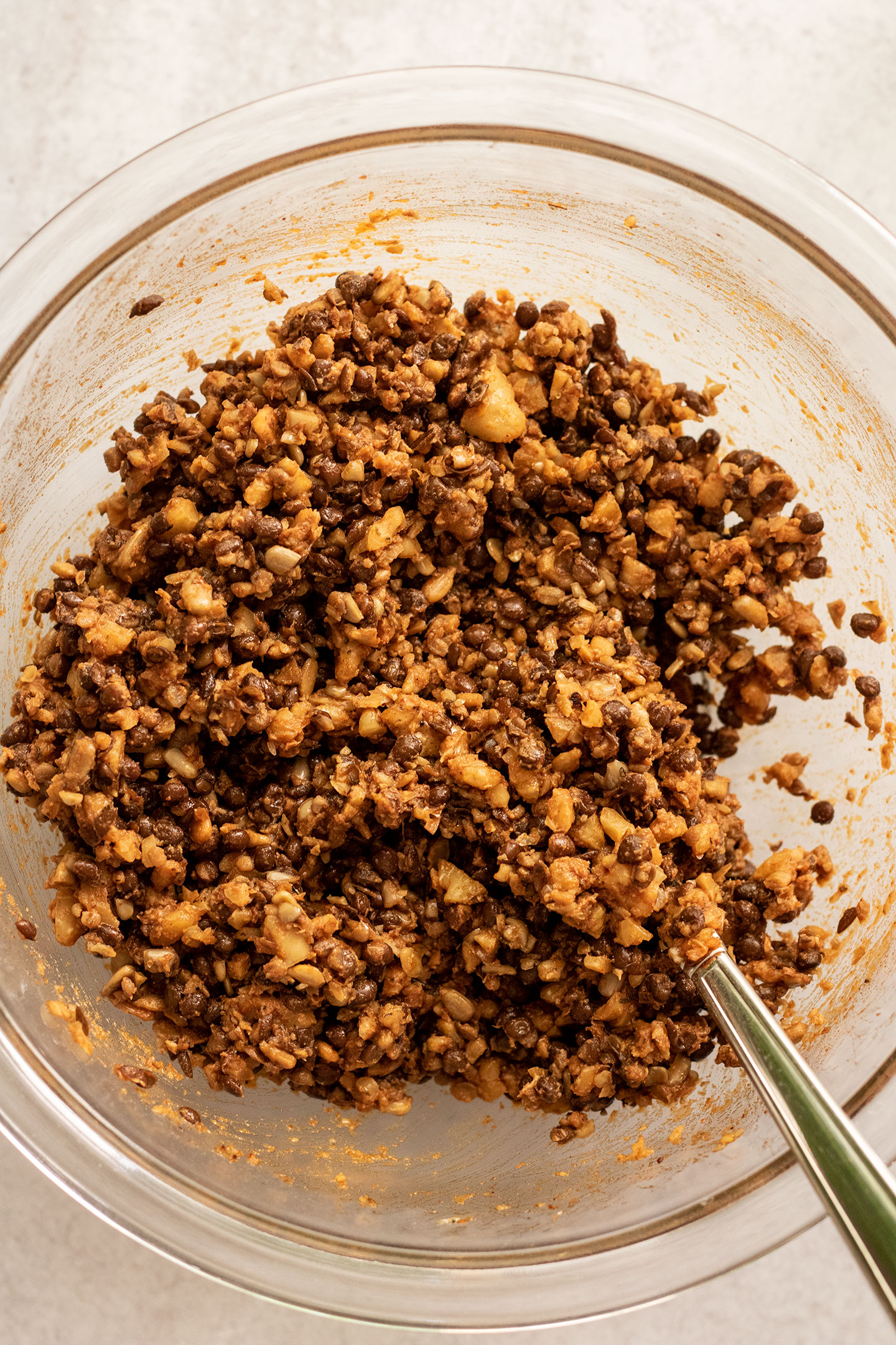 Tossed lentil, walnuts and chopped sunflower seeds mixed with spices in a bowl.