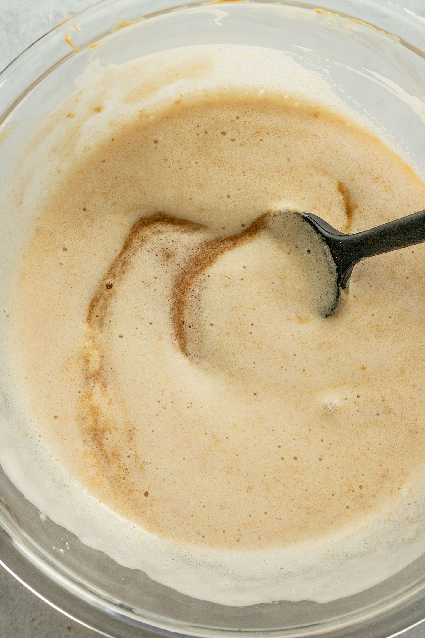 Frothed aquafaba being mixed with the peanut butter and brown sugar in a mixing bowl.