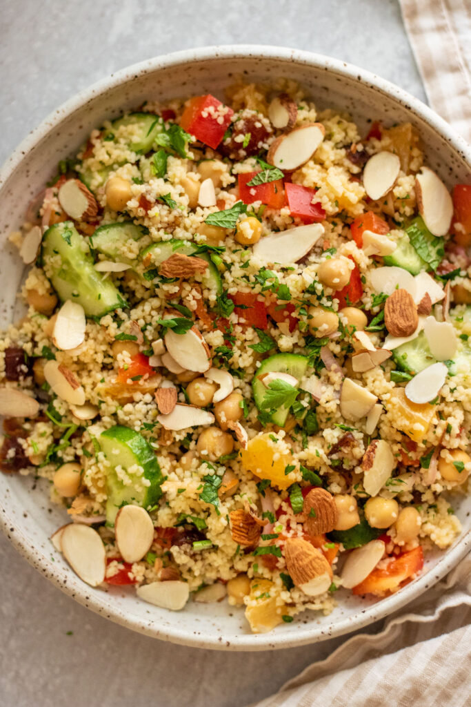 Close up on a plate of couscous chickpea salad tossed with almonds and a citrus vinaigrette.