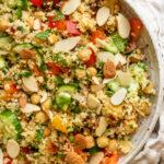 Close up top down view of a bowl of vegan couscous salad with sliced almonds, dried fruit, veggies and citrus dressing.