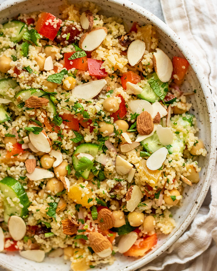 A giant grain bowl of veggies, couscous, dried fruit, and veggies tossed with citrus dressing.