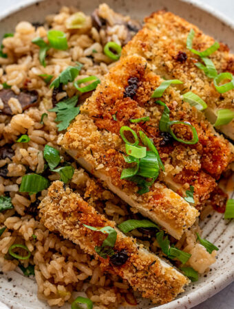 Close up of crispy panko crusted tofu topped with chili oil and scallions.