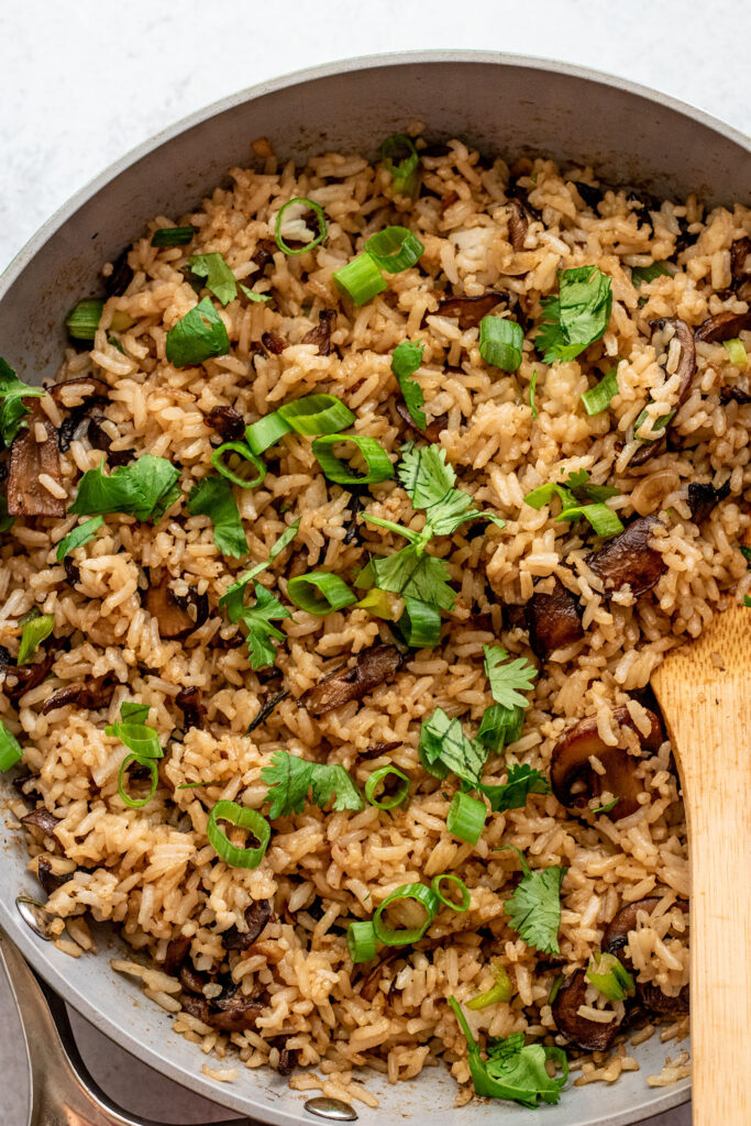 Fried rice fully mixed in a pan topped with spring onions and cilantro.
